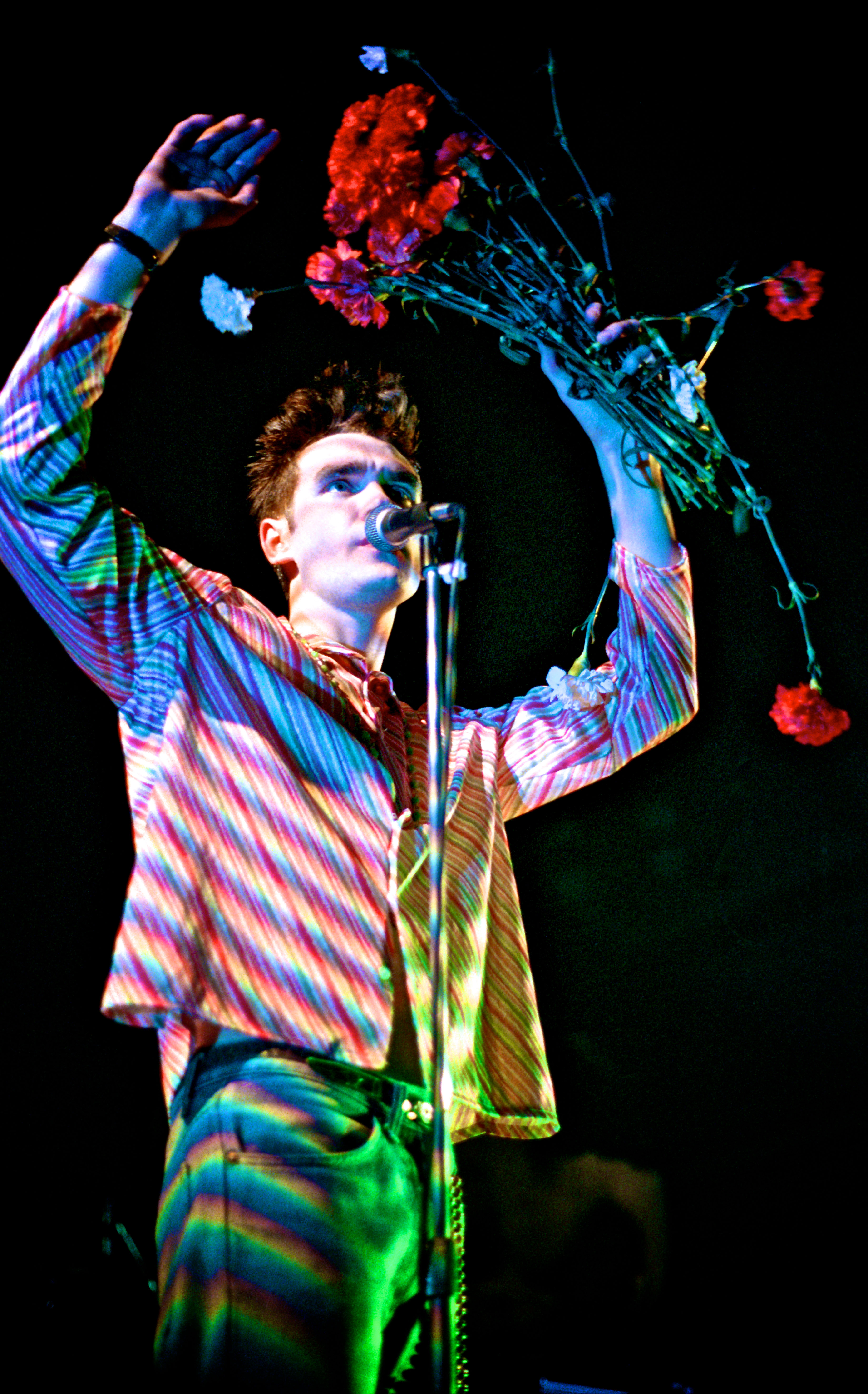 Morrissey performing at a Smiths concert, holding a bouquet of flowers aloft.