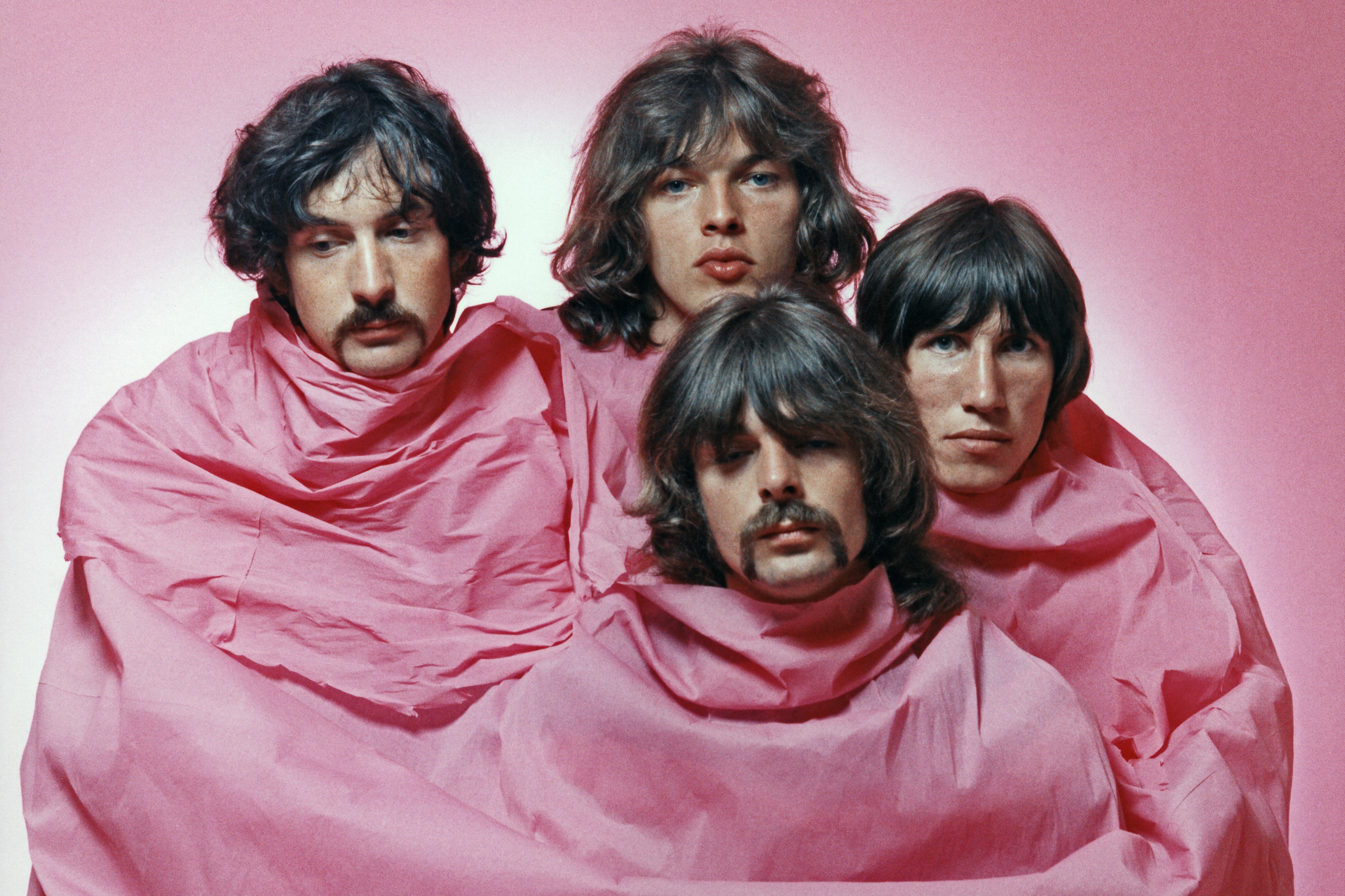 Pink Floyd members Nick Mason, David Gilmour, Rick Wright, and Roger Waters shrouded in pink fabric.