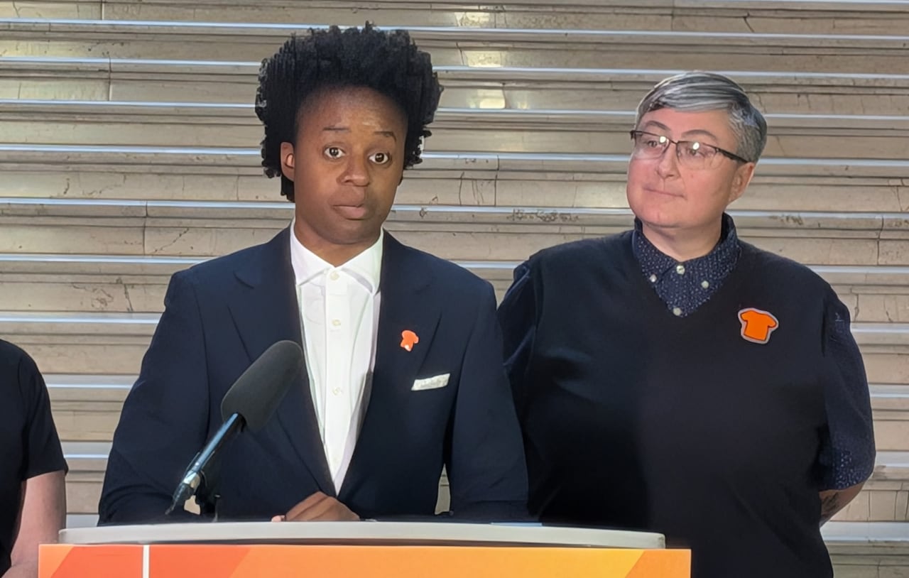 A person at a podium with a black blazer and dark hair