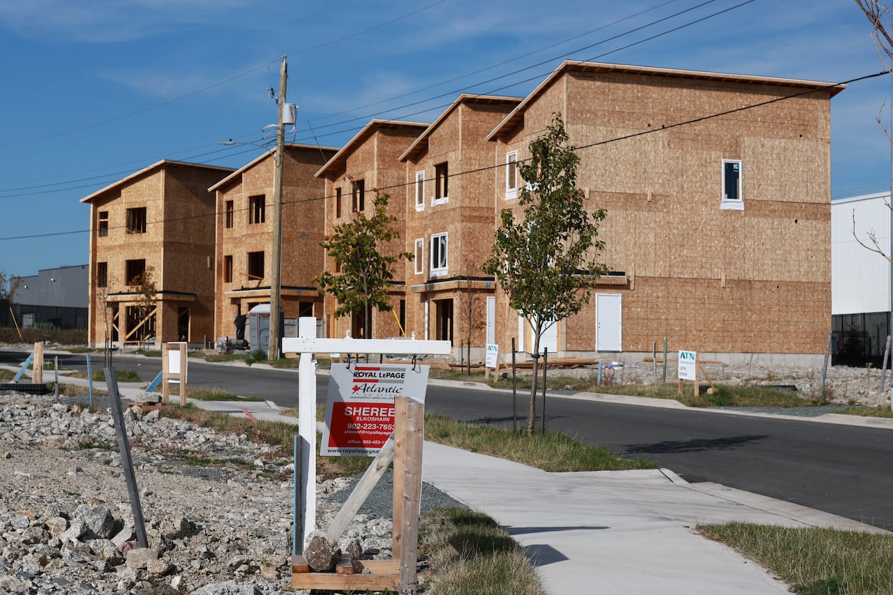 Houses under construction are seen in the distance, with a realtor's sign in the foreground.