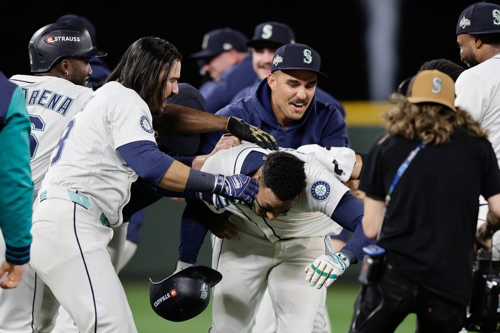 Seattle Mariners players celebrate with Jorge Polanco, center, after he hit the game-winning RBI single in the 15th inning in Game 5 of baseball