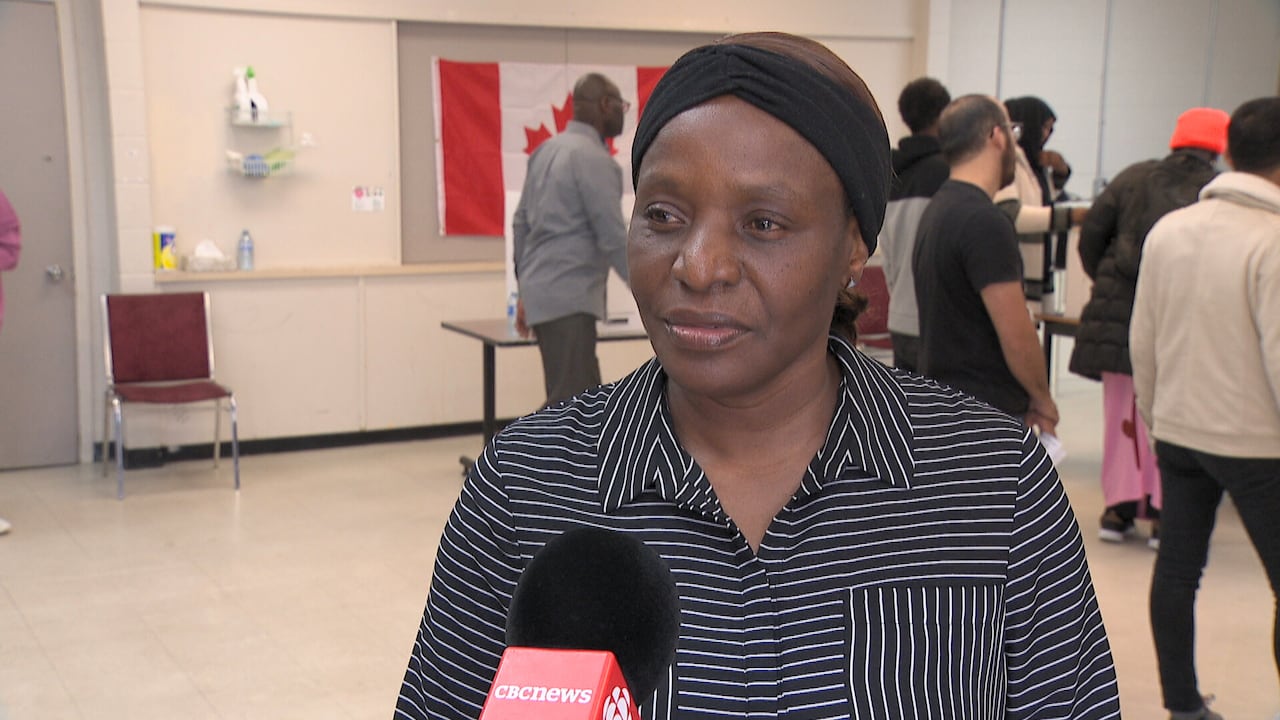 Woman standing in classroom talking into microphone held by reporter