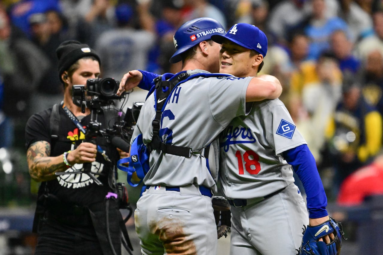 A baseball catcher and pitcher hug one another after winning a big game