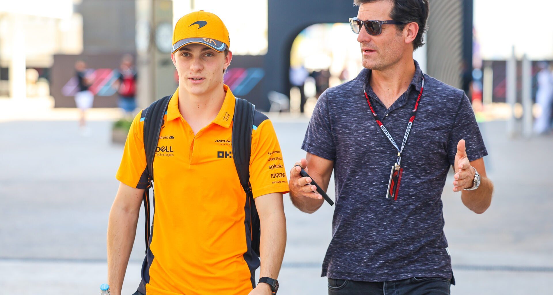 Piastri and manager Mark Webber walk the F1 paddock chatting