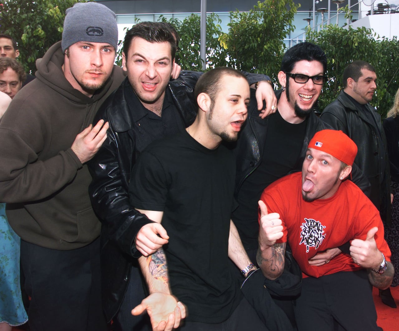 A group of five men pose for a photo on an awards red carpet. 