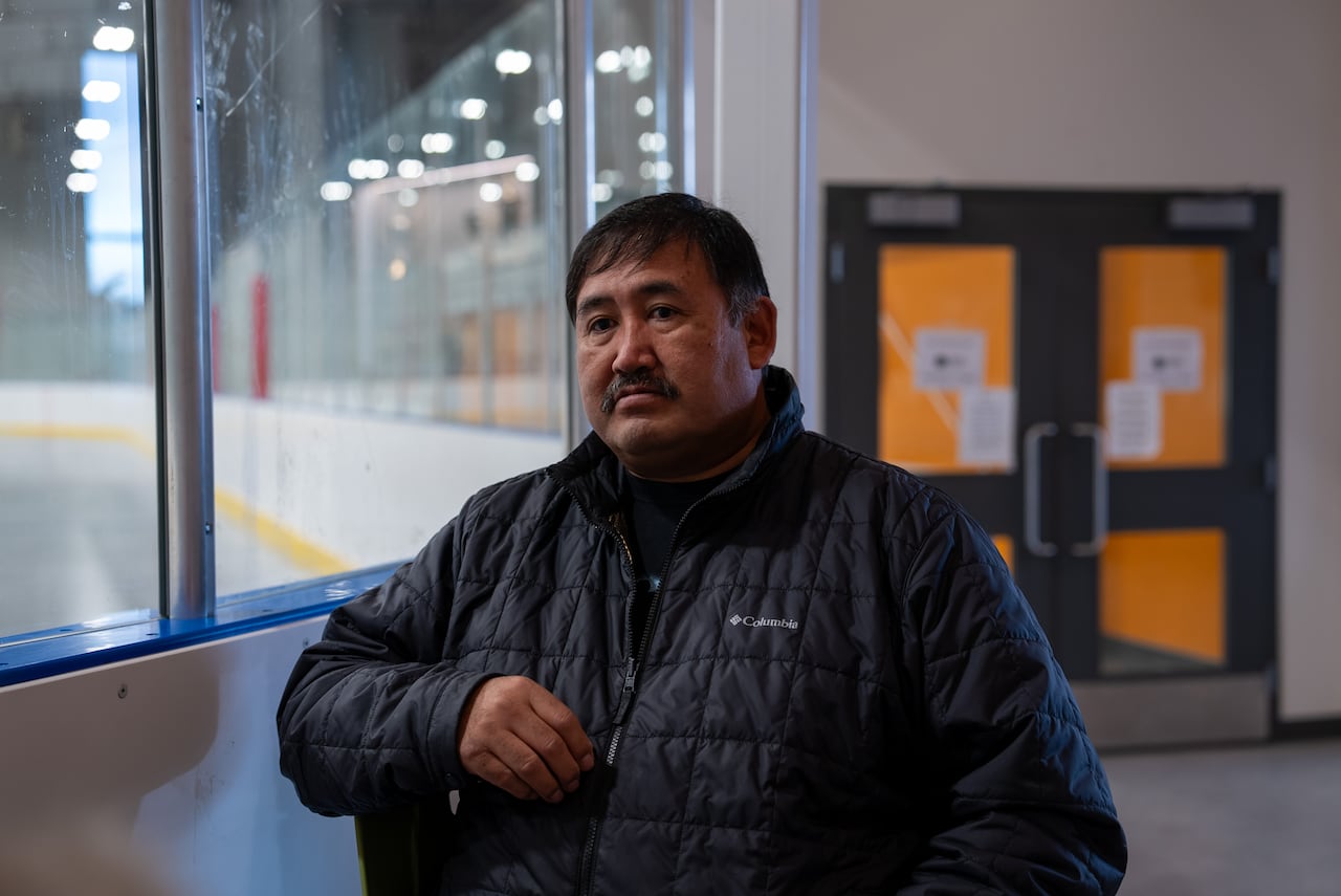 A man stands near an indoor hockey rink.