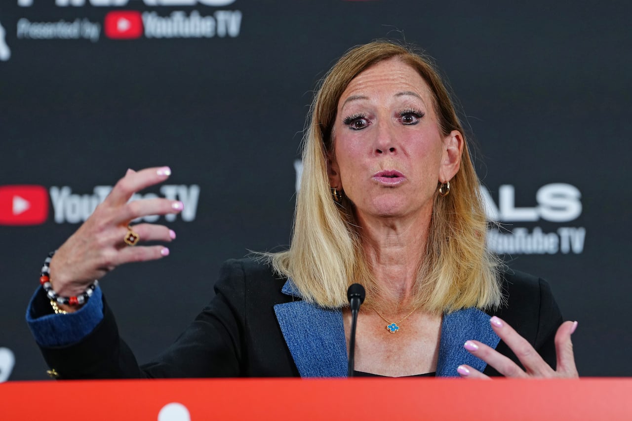woman with blond hair in dark suit gestures as she speaks