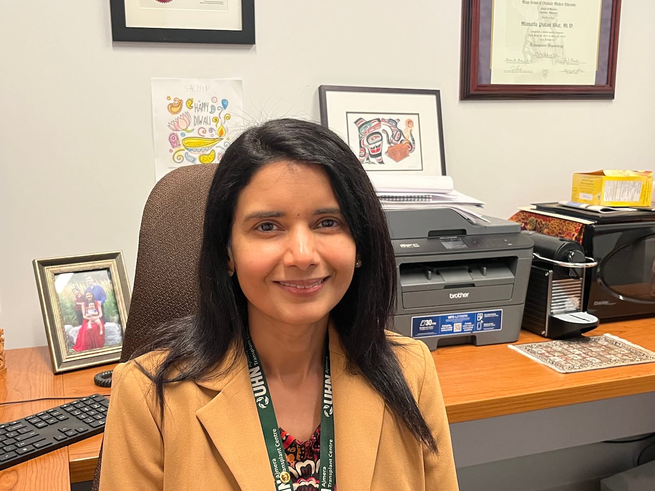 A woman with dark hair is scene at her office desk.