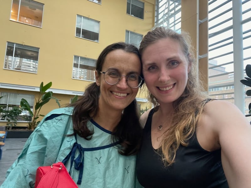 A woman in a hospital gown poses for a photo with a woman in regular clothing.