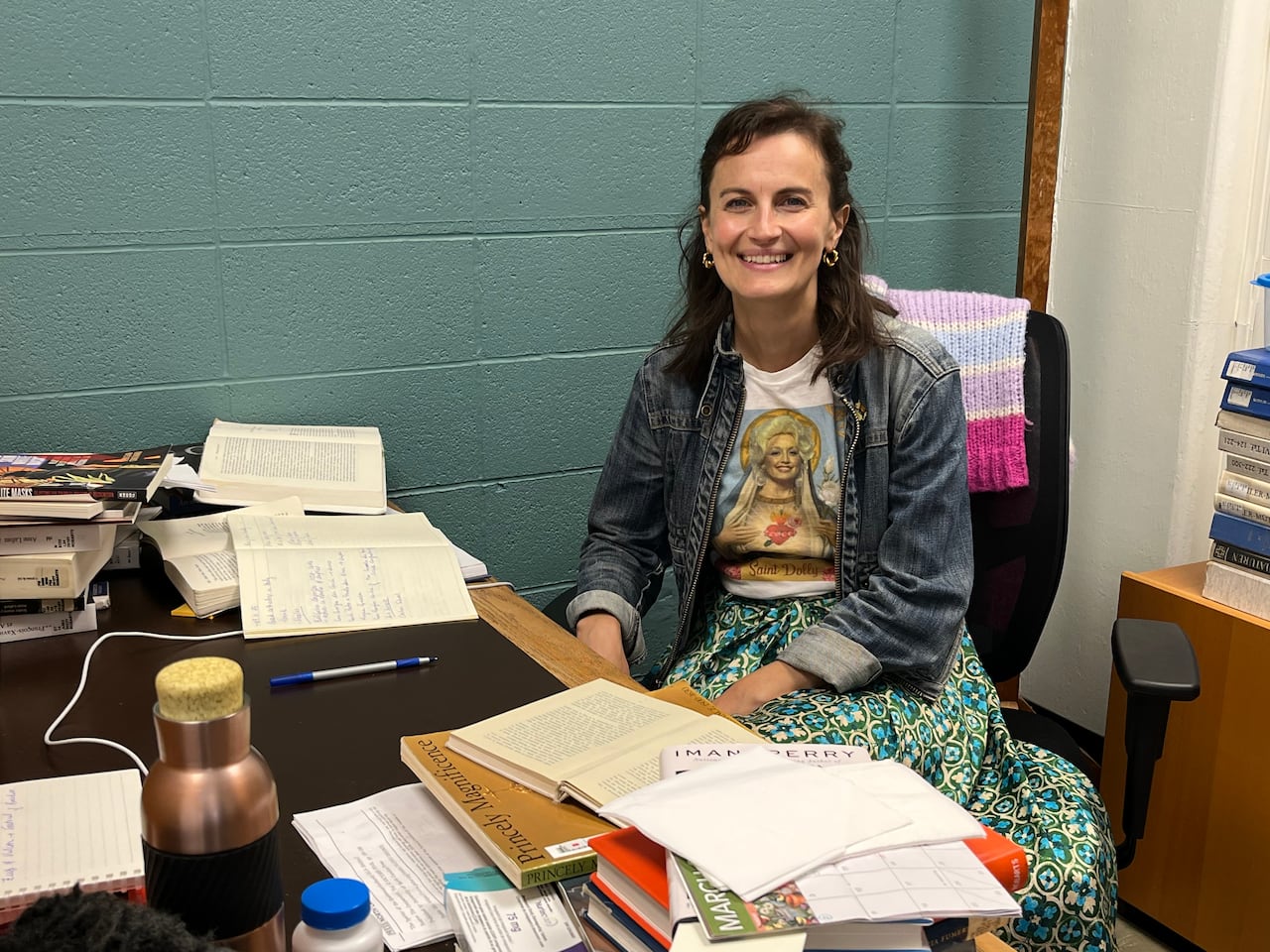A woman smiles from behind a desk