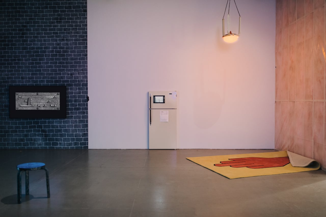 A fridge door with a screen on it and a large red and yellow tapestry