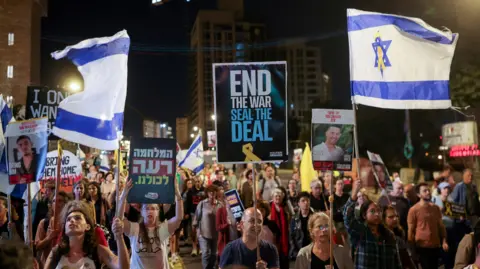 Reuters Demonstrators carry flags and placards as families of hostages and their supporters protest ahead of the two-year anniversary of the deadly October 7, 2023, attack on Israel by Hamas, demanding the immediate release of all hostages and the end of the war in Gaza, in Jerusalem, October 4, 2025. 