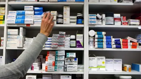 PA Media Stock image of a pharmacist stocking medicine onto shelves.