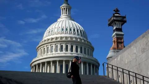 EPA A tourist passes the US Capitol in Washington, DC