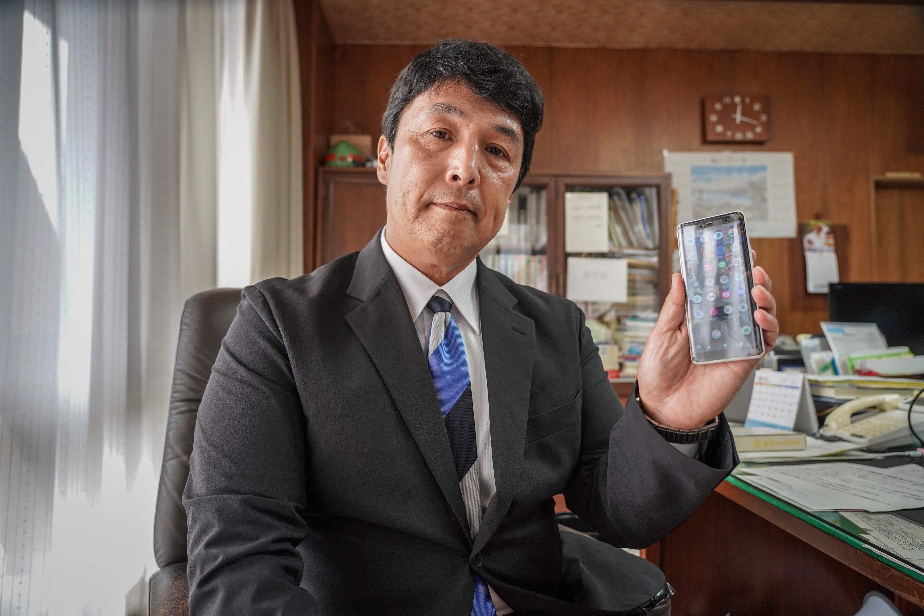 Toyoake Mayor Masafumi Kouki poses with his phone in Toyoake, Aichi Prefecture, Japan, Oct. 7, 2025. (AFP Photo)