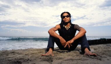 Lenny Kravitz sitting in a beach with the sea in the background
