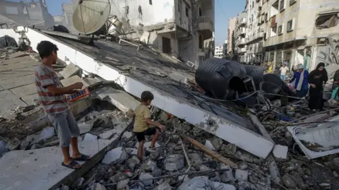 EPA Family members inspect the rubble of their former home following an air strike during an Israeli military operation in Gaza City, Gaza Strip, 3 October 2025