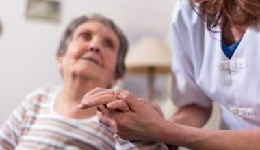 Nurse holding an elderly patients hand