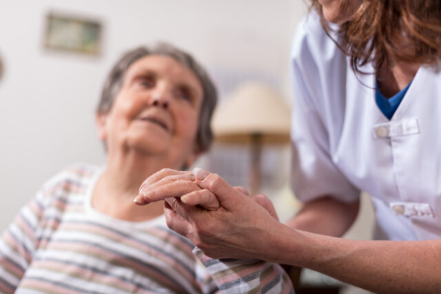 Nurse holding an elderly patients hand