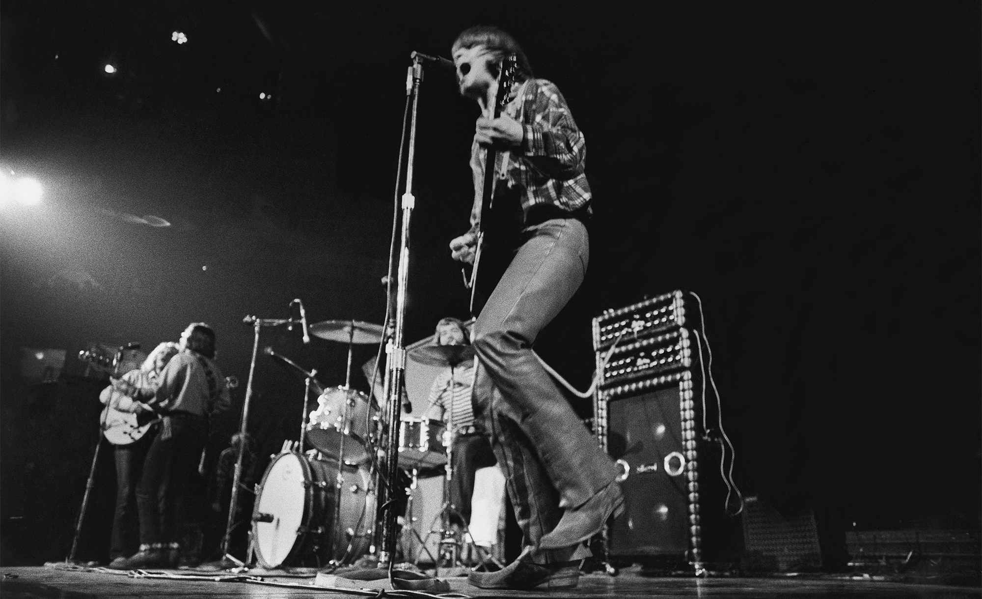 Rock and roll band Credence Clearwater Revival in performance, Looking up at lead singer (middle) John Fogerty with drummer Doug Clifford beyond and other members Stu Cook and Tom Fogerty in background to left.