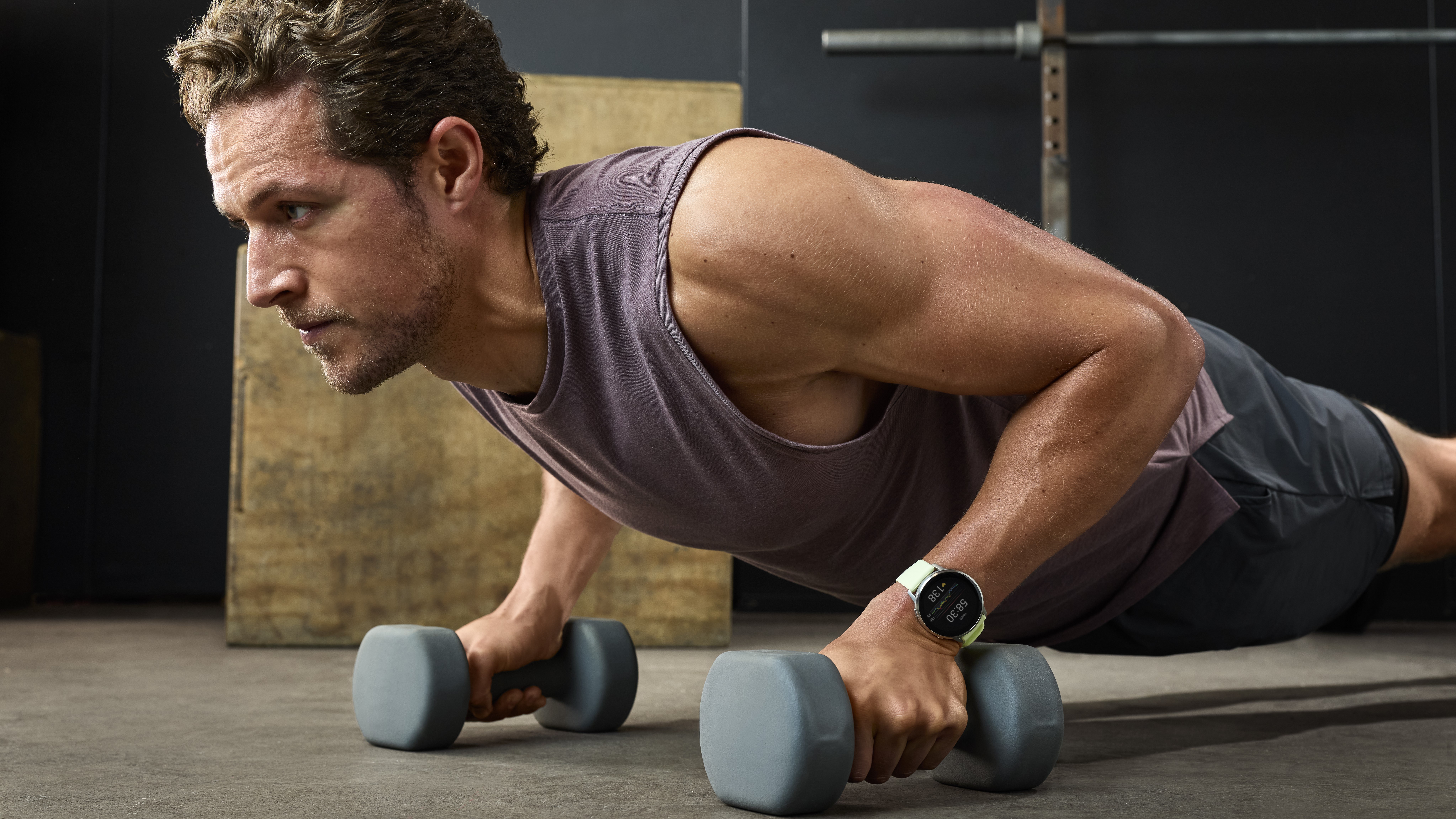 A photo of the Garmin Venu 4 on a man's wrist as he does weighted push-ups.