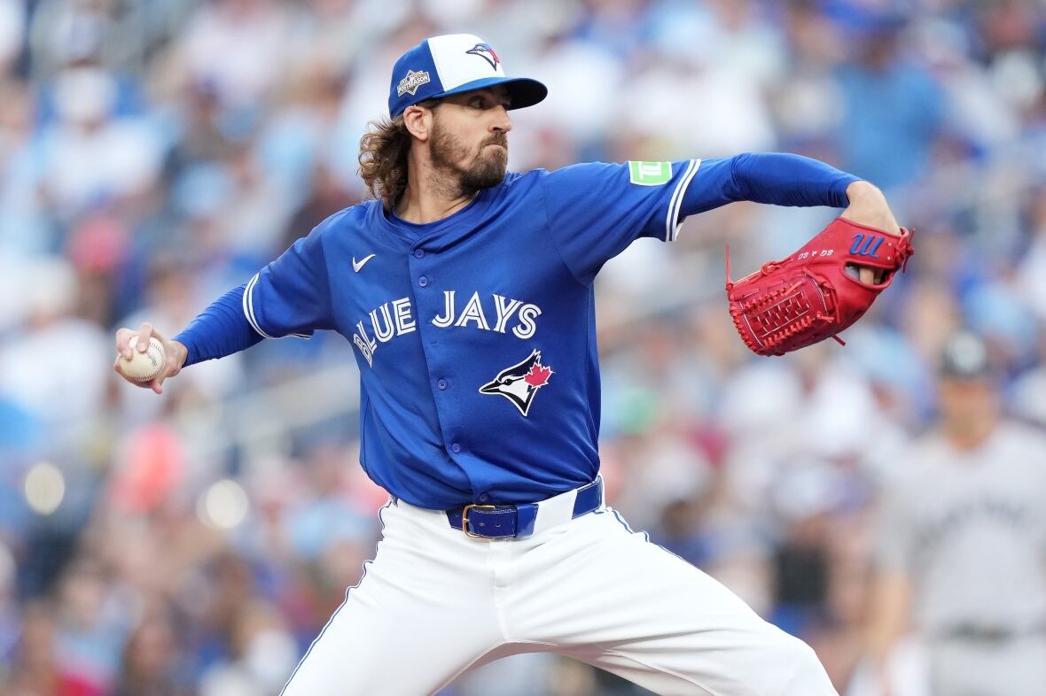 A baseball pitcher wearing white pants and a blue jersey and hat throws the ball.