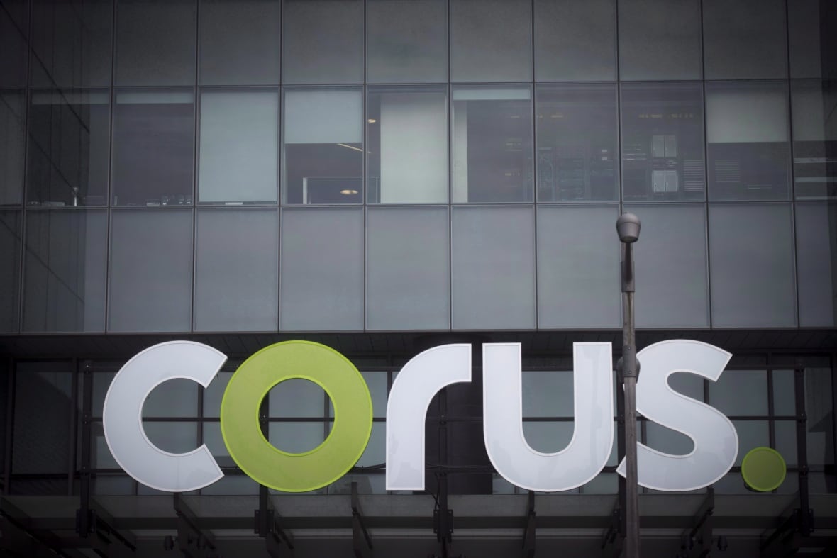 A sign saying "corus" is seen outside of a glass building.