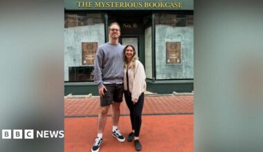 Ally Fir (R) and Matt Rawlings (L) pictured outside their shop before it opened. The windows are empty and there is a sign saying "The Mysterious Bookcase".