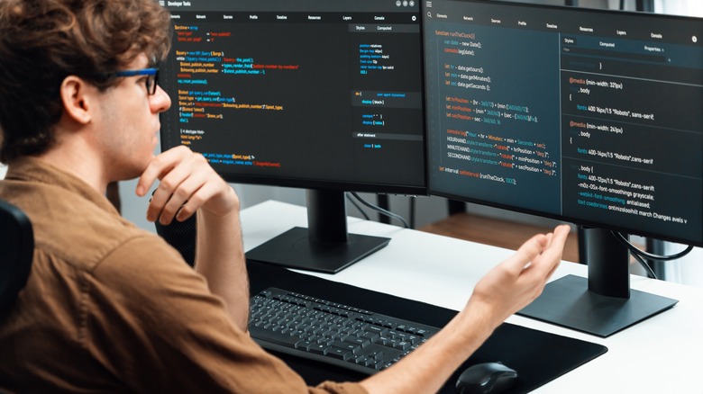 A person working with two PC monitors