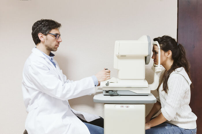 Doctor conducting eye exam on woman using medical equipment, illustrating cases of self-diagnosed patients proven wrong.