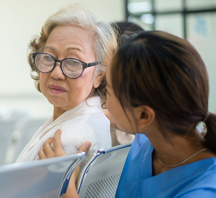 Elderly woman consulting with nurse showing concern, illustrating self-diagnosis and doctor correction concept.