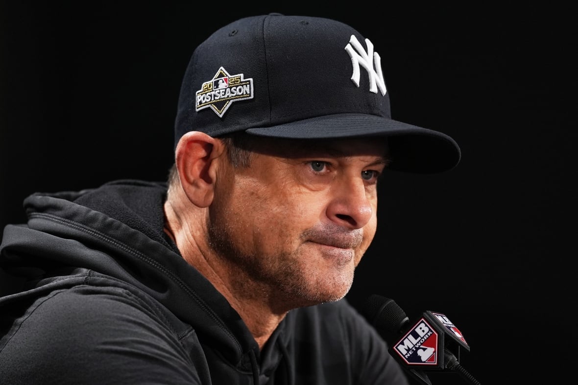 A man in a baseball cap, sitting in front of a microphone.