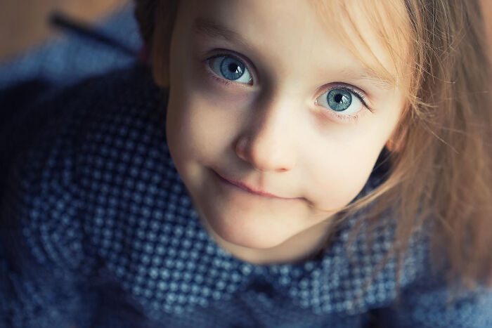 Close-up of a young child with blue eyes and a serious expression, illustrating patients brushing off terrifying symptoms.