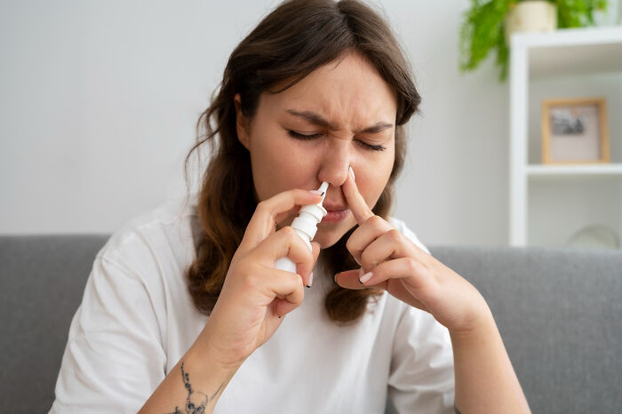 Young woman using nasal spray, illustrating patients brushing off terrifying symptoms as normal to doctors' horror.