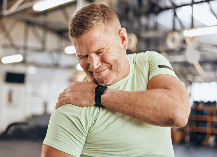 Man in a gym holding his shoulder in pain, illustrating patients brushing off terrifying symptoms as normal.