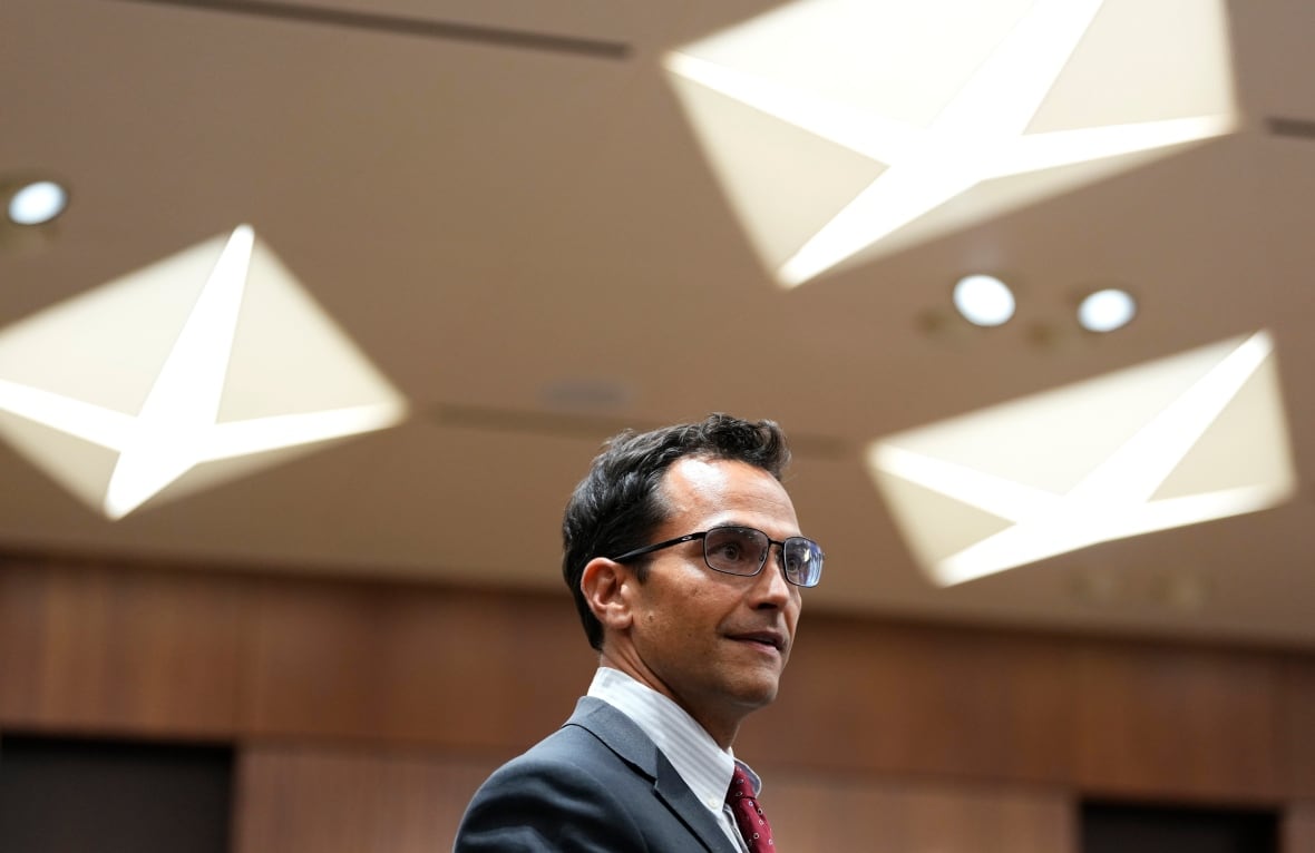 A man in a suit and tie stands in a well lit room.