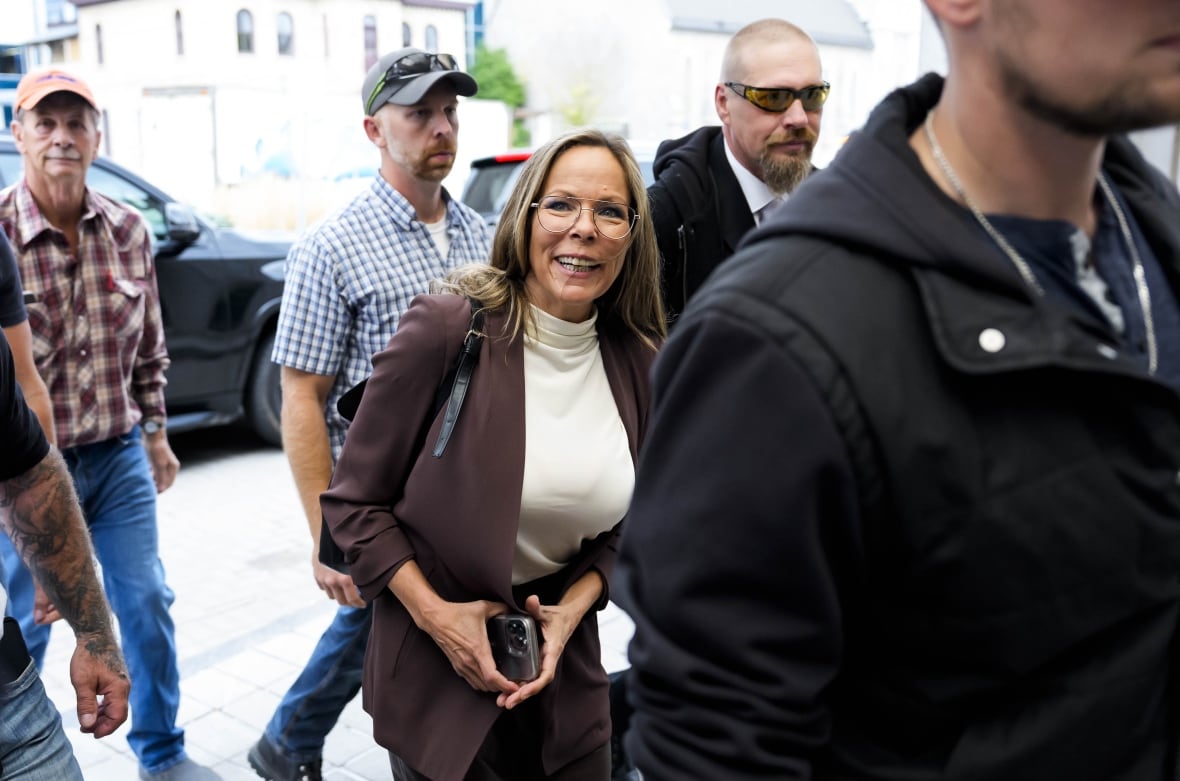 A woman smiles as she enters a city courthouse in early autumn.