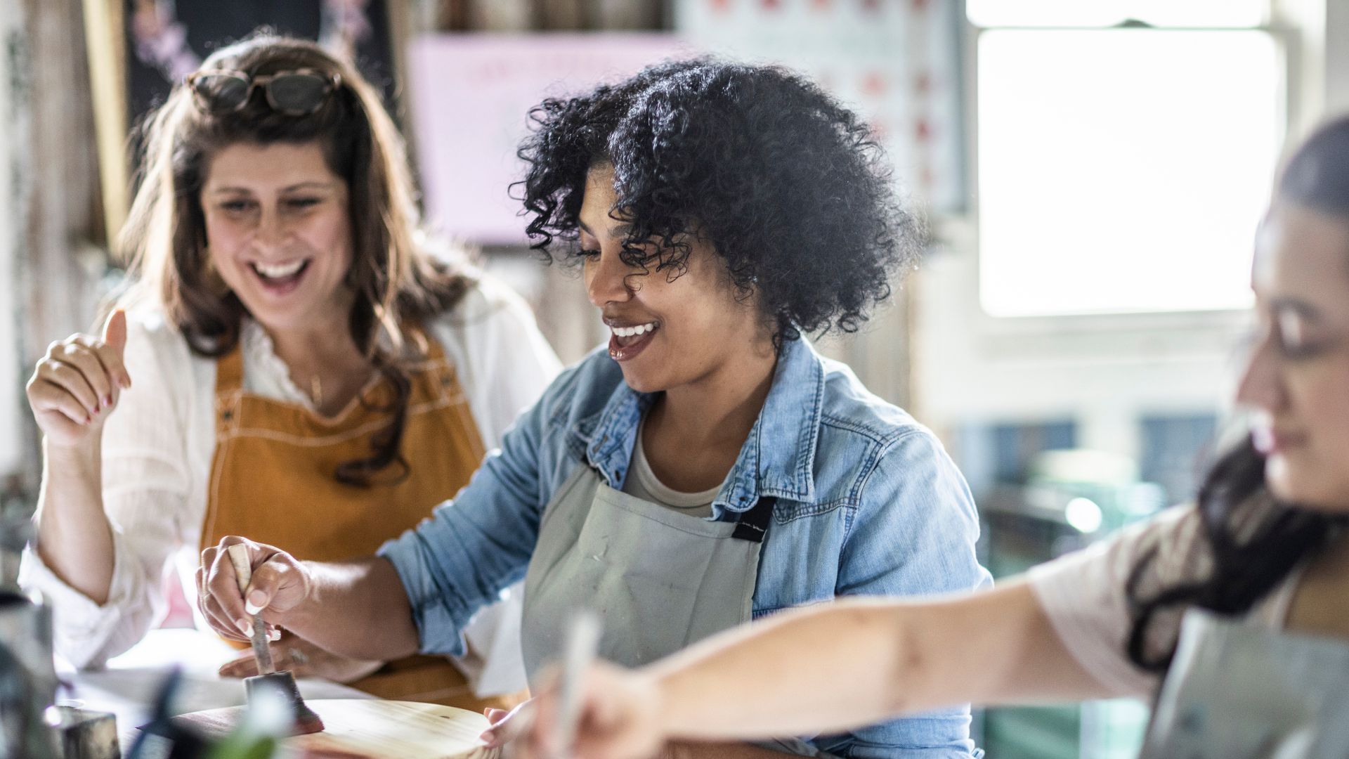 Women sitting at table painting and laughing