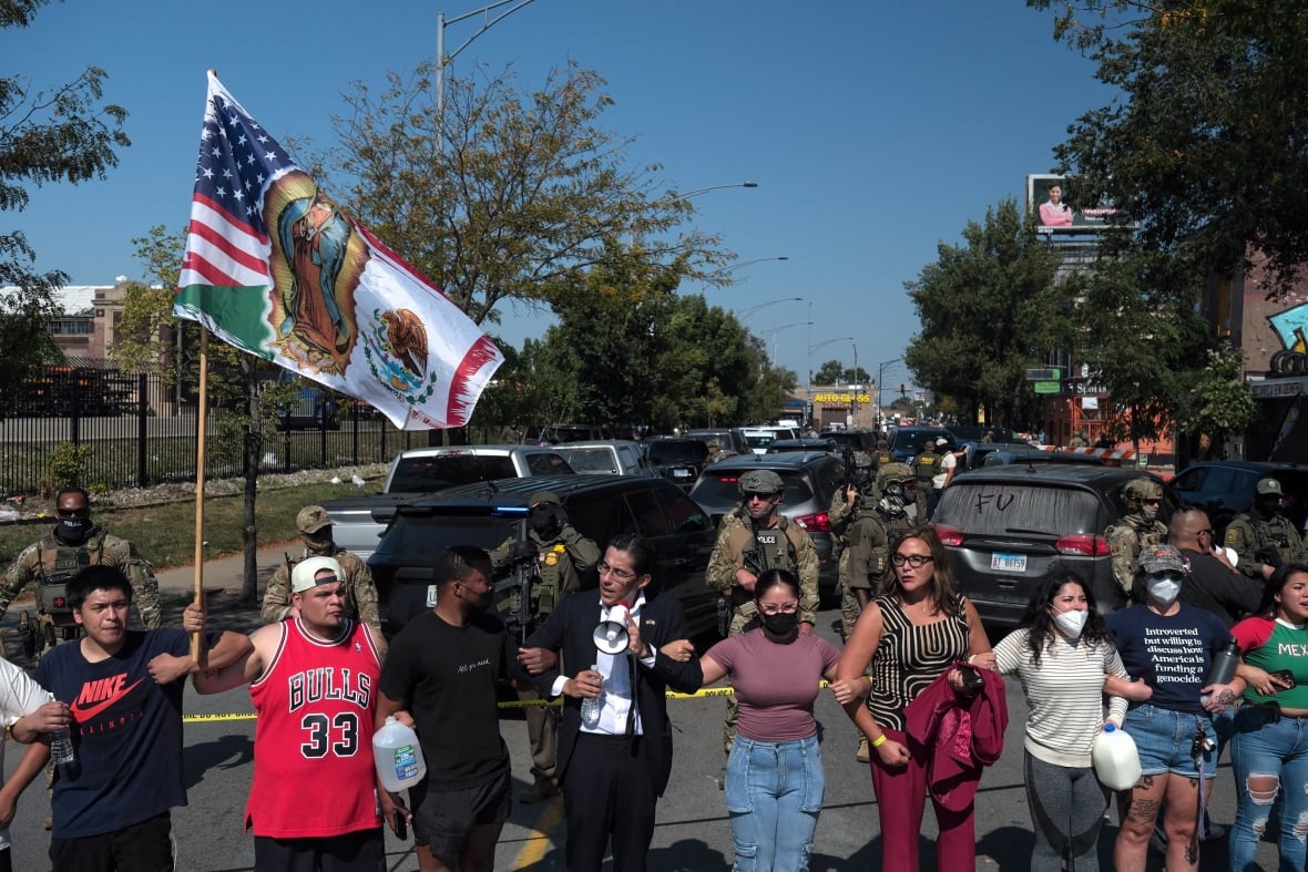 Demonstrators lock arms in a line as they face off with armed police on a street.