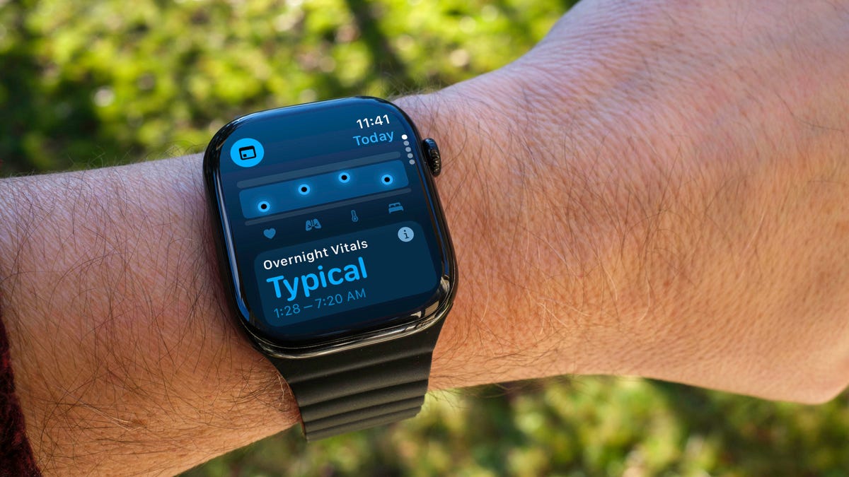 An Apple Watch on a wrist. The screen shows the Vitals app.