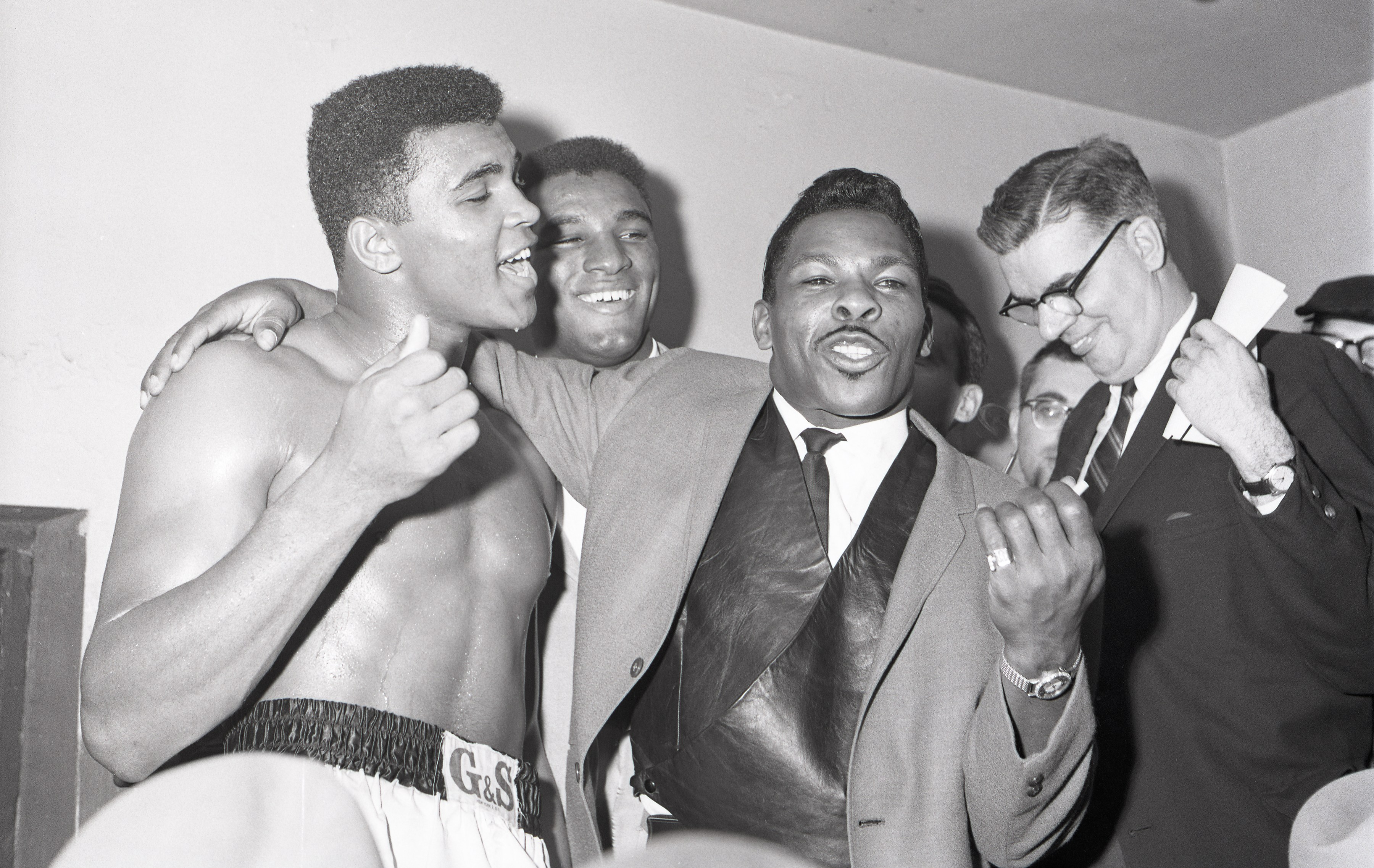 Cassius Clay (left) celebrates his win with brother Rudolph 'Rudy' Clay and Singer Lloyd Price (center) after his TKO win against Archie Moore.