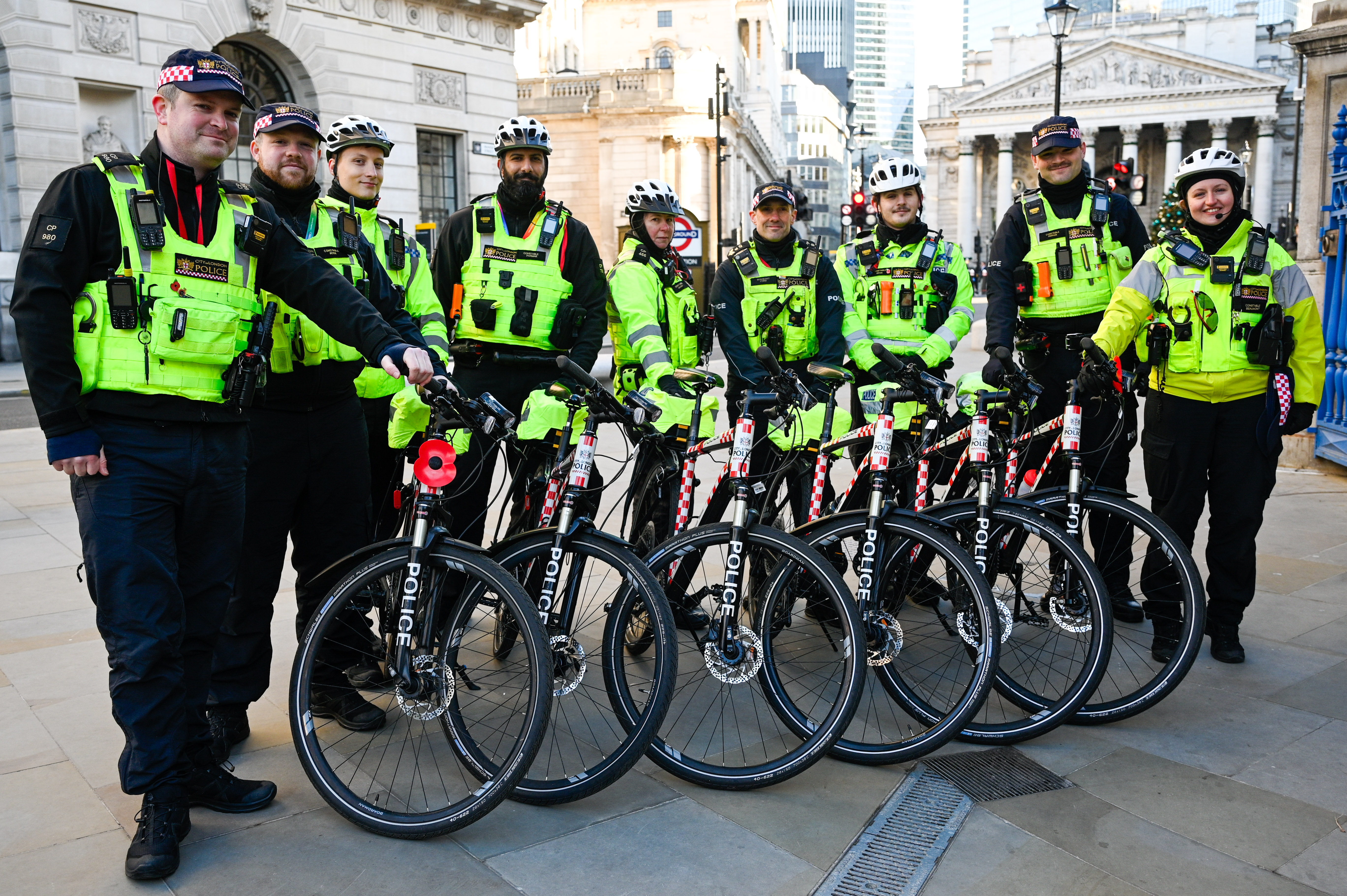 Members of the City of London Police Cycle Response Unit in fluorescent vests pose with their police bicycles.