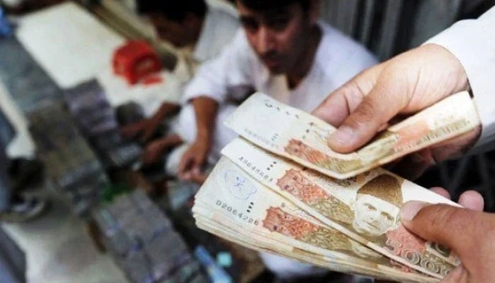 The representational image shows a persons hands holding Pakistani Rupee banknotes. — AFP/File
