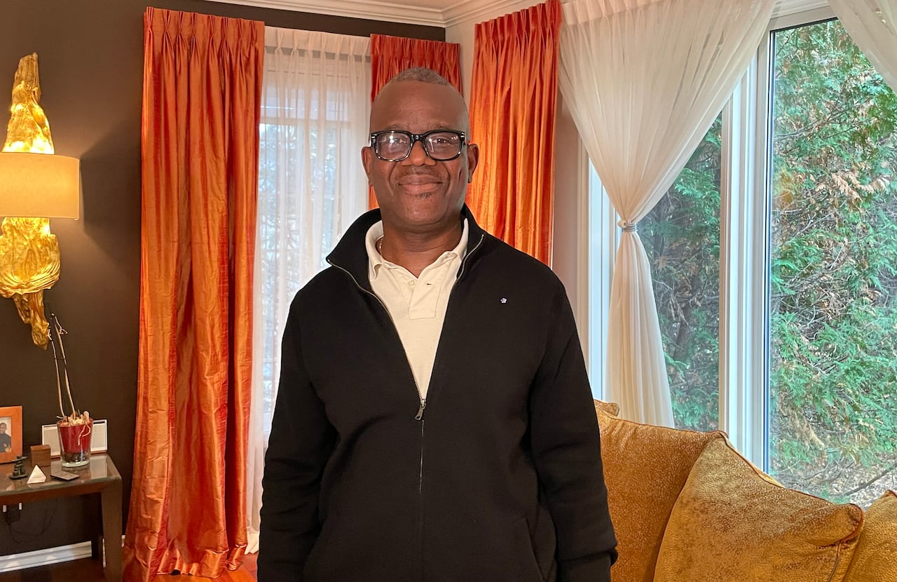 A man stands in a living room and smiles at the camera.