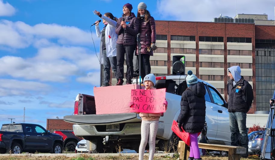 Several people stand in the back of a truck as part of a protest.