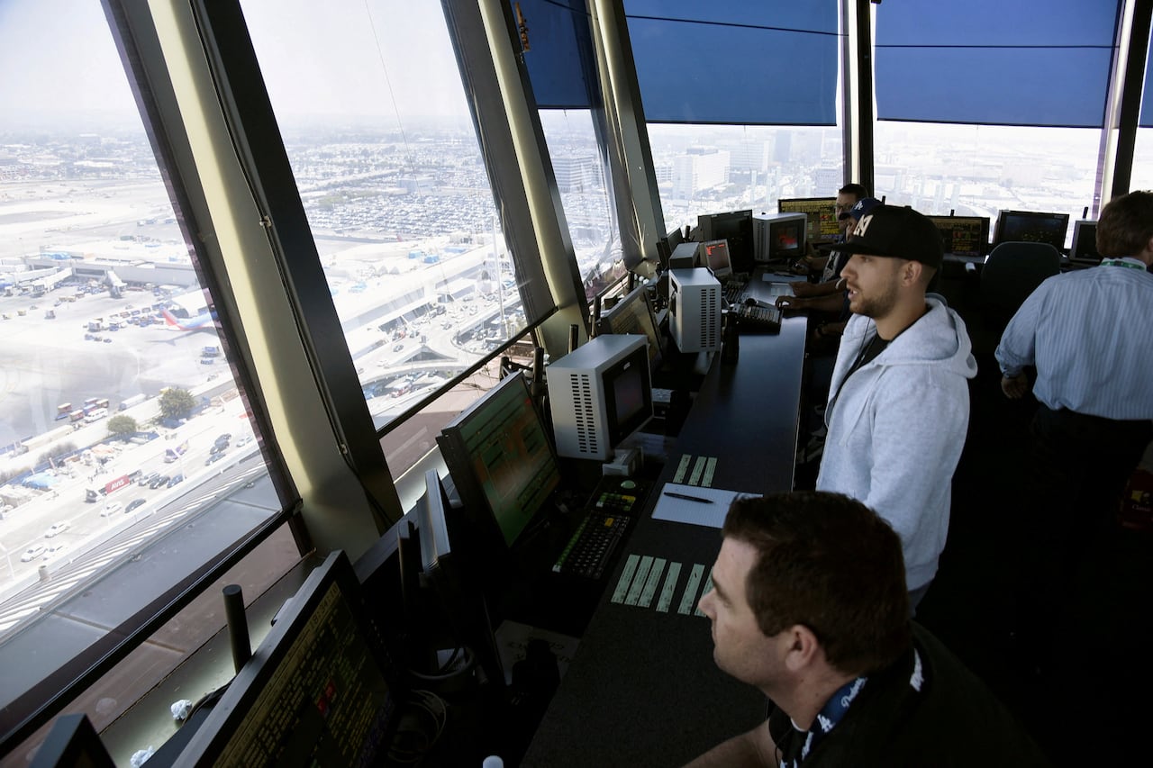 Two air traffic controllers look at planes from the tower.