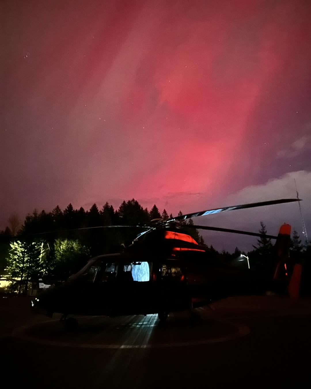 A helicopter sits with a red sky 