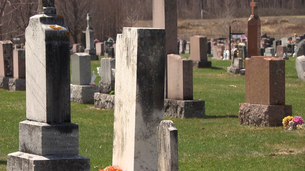 Headstones stand in rows on a sunny day.