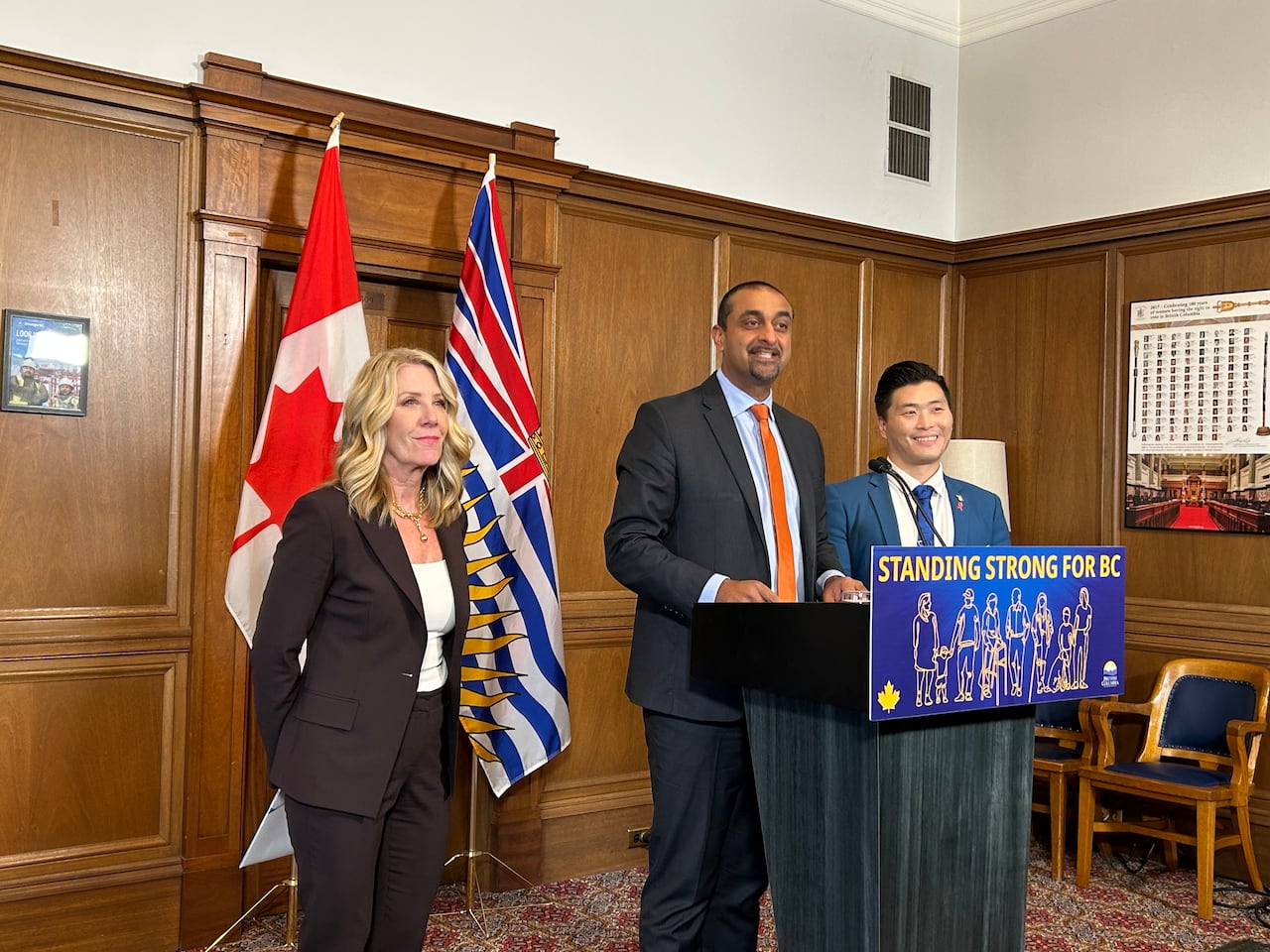 a man stands at a podium with two other people