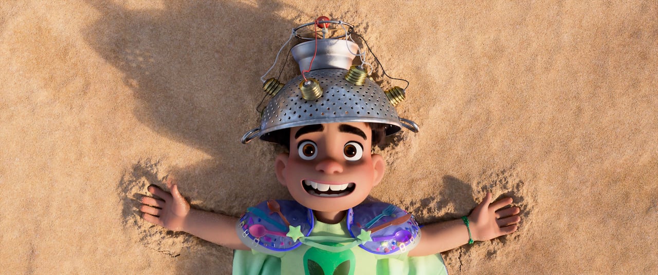 An animated image of a little boy lying on a beach and wearing a colander affixed with wires on his head is shown. 